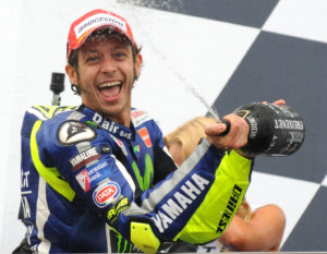 Italys Valentino Rossi of Movistar Yamaha sprays sparkling wine on the podium, after winning the Moto GP race at the British Grand Prix at Silverstone, England, Sunday, Aug. 30, 2015. (AP Photo/Rui Vieira)