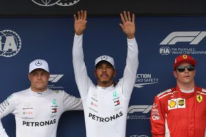 Mercedes' British driver Lewis Hamilton (C), who took the dominant pole position, celebrates with his teammate Mercedes' Finnish driver Valtteri Bottas, next to Ferrari's Finnish driver Kimi Raikkonen (R) on the podium after the qualifying session on the eve of the Formula One Hungarian Grand Prix at the Hungaroring circuit in Mogyorod near Budapest, Hungary, on July 28, 2018. Lewis Hamilton finished ahead of Mercedes' Finnish driver Valtteri Bottas and Ferrari's Finnish driver Kimi Raikkonen. / AFP PHOTO / ATTILA KISBENEDEK