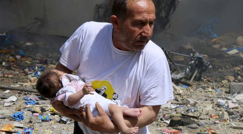 Mitt i kriget. En man med ett spädbarn efter ett bombangrepp av syriska regeringsstyrkor i staden Aleppo, juni 2015.
