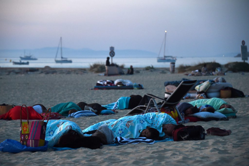 TOPSHOT - People camp and sleep on the beach in Bormes-les-Mimosas, southern France, at sunrise on July 27, 2017 where they took refuge after being evacuated from their campsite due to the fire.
Thousands of tourists fled to the safety of public shelters after a fire broke out overnight in the village of Bormes-les-Mimosas, on the Cote d'Azur, and swept towards the area's campsites. Local residents joined firefighters in southern France on July 26, 2017 to battle blazes that have forced over 10,000 people to flee and left chunks of coastal forest a blackened mess. / AFP PHOTO / ANNE-CHRISTINE POUJOULAT / TT / kod 444