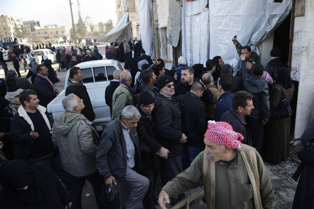 Syrians men displaced from east Aleppo last month wait for a security check to return to their homes in Hanano district in eastern Aleppo, Syria, Sunday, Dec. 4, 2016. On Nov. 26, government forces stormed the Hanano district, their deepest incursion into east Aleppo in more than four years. Abdul-Ghani Kassa, Aleppo's deputy governor, said some 750 families have so far returned the Hanano, a district subjected to wide destruction during government shelling and airstrikes on the area. (AP Photo/Hassan Ammar)