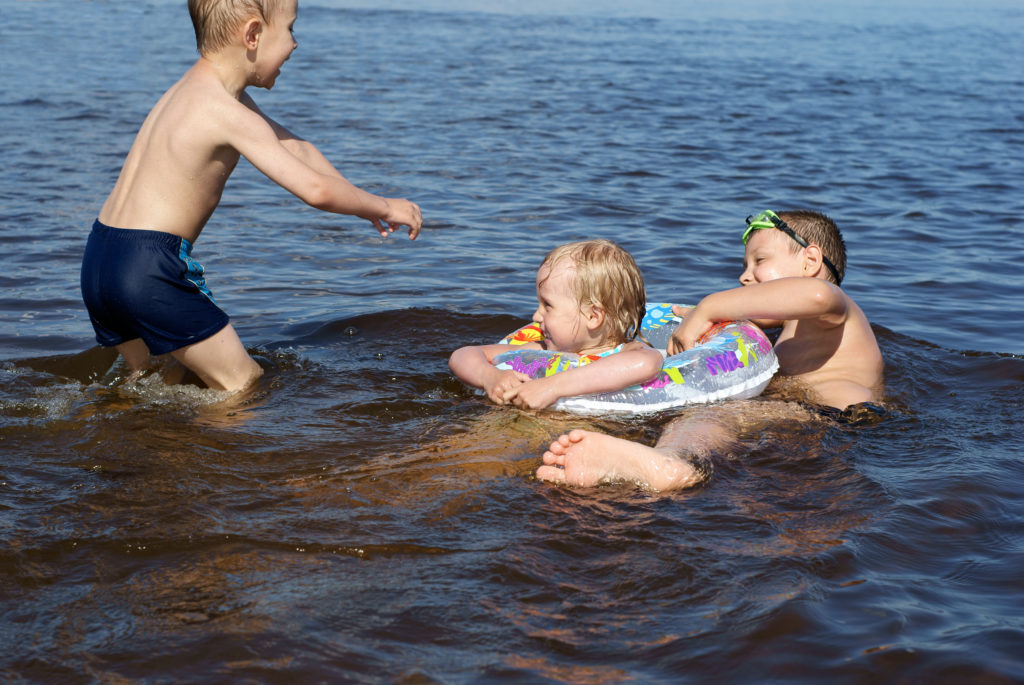 Two boys and girl play in the river