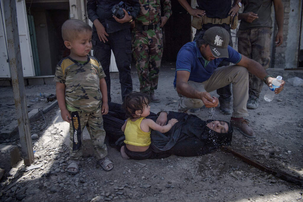 slutstriden mot is i mosul. flyende familjer flyr is genom gamla stans trnga grnder. en mamma som flytt is med sina tv barn dr av utmattning framfr deras gon.